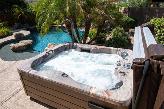 A picture of a filled hot tub, on a stone patio during summer. 